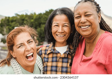 Happy multiracial elderly friends smiling in front of camera - Senior women hugging each other outdoor - Powered by Shutterstock