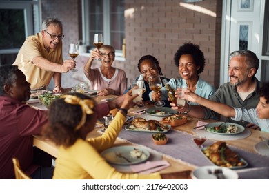 Happy multiracial extended family toasting and having fun together during meal on a patio.