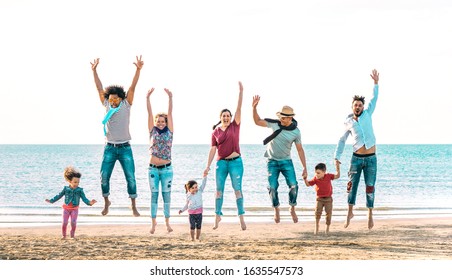 Happy Multiracial Families Jumping Together At Beach Holding Hands - Summer Vacation Concept With Young Mixed Race People Having Genuine Fun Outdoors Enjoying Sunset - Vivid Azure Backlight Filter