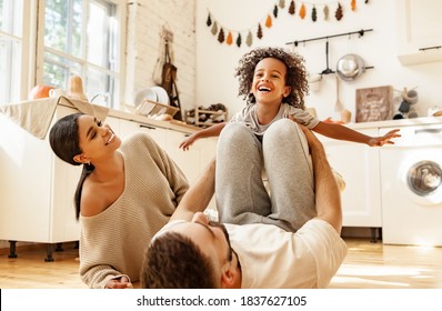 Happy Multiracial Family: Diverse Parents Playing With Son In Cozy Kitchen On Weekend Day At Home
