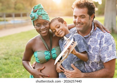 Happy Multiracial Family Enjoy Day At City Park - Pregnant African Mother, Caucasian Father And Mixed Race Son Enjoy Day Outdoor