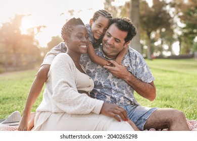 Happy Multiracial Family Enjoy Picnic At City Park - African Pregnant Woman With Caucasian Husband And Mixed Race Child Outdoor