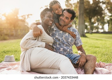 Happy Multiracial Family Hugging Each Other At City Park - African Pregnant Woman With Caucasian Husband And Mixed Race Child Enjoy Picnic Outdoor