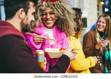 Happy multiracial friends eating takeaway food outdoor - Focus on african girl face - Powered by Shutterstock