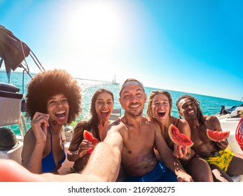 Happy multiracial friends eating watermelon while doing sea tour with sailing boat - Summer and vacation concept - Main focus on center man face