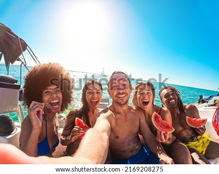 Happy multiracial friends eating watermelon while doing sea tour with sailing boat - Summer and vacation concept - Main focus on center man face