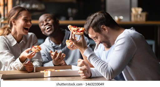 Happy Multiracial Friends Gathering In Restaurant Or Bar Tasting Sharing Pizza Laughing On Joke, Excited Diverse Young People Have Fun Meeting Enjoy Tasty Italian Food From Takeaway Delivery