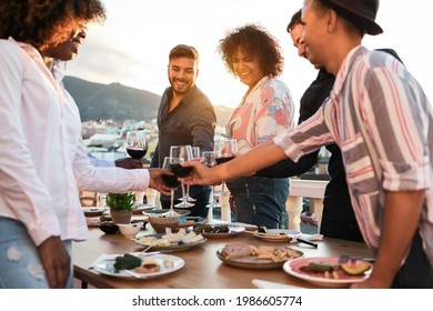 Happy Multiracial Friends Having Dinner And Cheering With Wine Outdoor At Home - Main Focus On Center Man Face