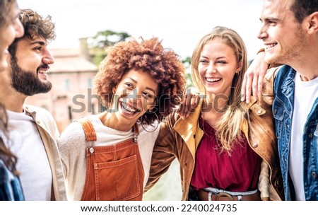 Happy multiracial friends having fun walking on city street - Group of young people laughing and hugging together outside - Youth community and friendship concept with guys and girls hanging out