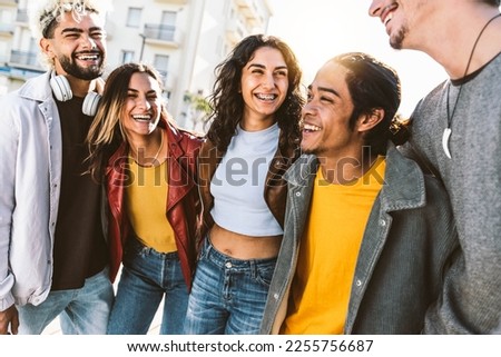 Happy multiracial friends having fun together walking on city street - Group of young people enjoying weekend hanging outside - Life style concept with guys and girls smiling and laughing out loud