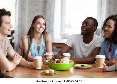 Happy multiracial friends spending free time together in cafe, having pleasant conversation, laughing students enjoying drinking coffee in cardboard cups, having fun in coffeehouse - Powered by Shutterstock