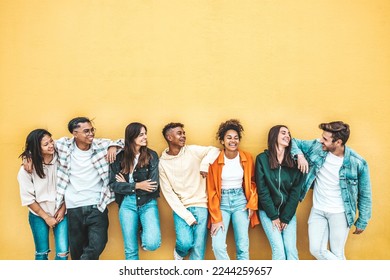 Happy multiracial friends standing over isolated background - Cheerful young people socializing outdoors - University students laughing together on yellow wall - Youth culture and friendship concept - Shutterstock ID 2244259657