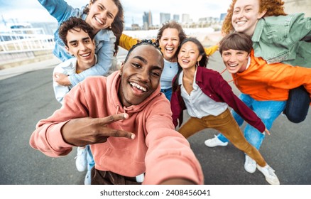 Happy multiracial friends taking selfie outside - Group of young people with arms up smiling at camera - Youth community with guys and girls hugging together - Powered by Shutterstock