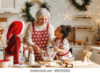 Happy multiracial kids help grandmother to cook Christmas cookies while standing together behind table in cozy kitchen at home, loving senior grandma baking with grandchildren during winter holidays - Powered by Shutterstock