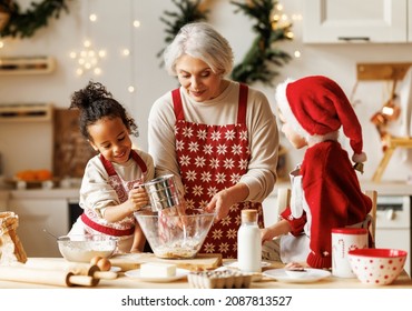 Happy multiracial kids help grandmother to cook Christmas cookies while standing together behind table in cozy kitchen at home, loving senior grandma baking with grandchildren during winter holidays - Powered by Shutterstock