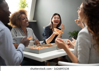 Happy multiracial millennial employees have fun enjoy tasty pizza during work lunch break in office, excited multiethnic diverse colleagues laugh eating delicious Italian food from takeaway delivery - Powered by Shutterstock