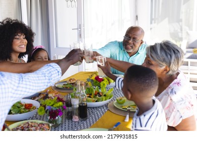 Happy multiracial multigeneration family toasting drinks while having lunch together at dining table. Home, food, unaltered, togetherness, love, childhood and retirement concept. - Powered by Shutterstock