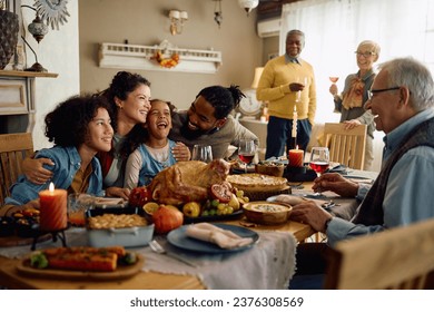 Happy multiracial parents and their kids laughing during family meal on Thanksgiving in dining room.  - Shutterstock ID 2376308569