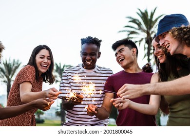 Happy multiracial people enjoying summer party at the beach - Diverse group of young adult students celebrating and laughing together with sparklers outdoors - Powered by Shutterstock