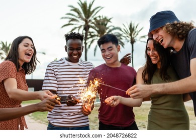 Happy multiracial people laughing and having fun together with sparkles outdoors - Young friends celebrating new year eve - Friendship and millennial eve celebration - Powered by Shutterstock