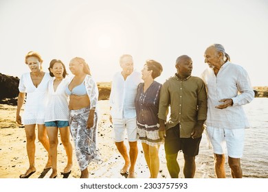 Happy multiracial senior friends having fun walking on the beach during summer holidays - Diverse elderly people enjoying vacations  - Powered by Shutterstock