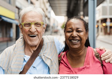 Happy multiracial senior friends having fun while waiting at the bus station - Powered by Shutterstock