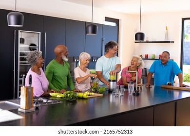 Happy multiracial senior friends talking and making smoothie on kitchen counter at retirement home. Unaltered, togetherness, support, assisted living, enjoyment, retirement and healthy food concept. - Powered by Shutterstock