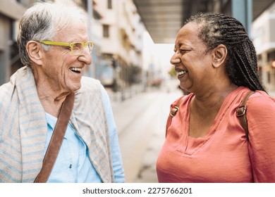 Happy multiracial senior friends talking while waiting at the bus station - Powered by Shutterstock