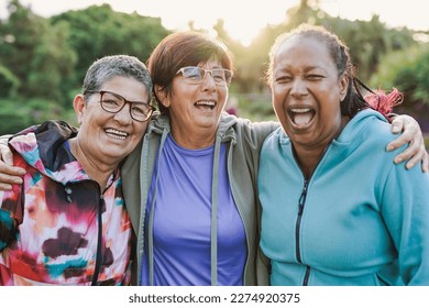 Happy multiracial senior women having fun together outdoor - Elderly generation people hugging each other at city park with sunrise in the background - Powered by Shutterstock