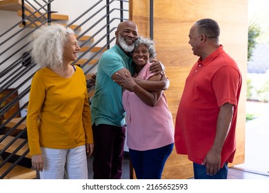 Happy multiracial seniors welcoming friends while standing at doorway in retirement home. Embracing, togetherness, entrance, visitor, greeting, unaltered, support, assisted living and retirement. - Powered by Shutterstock