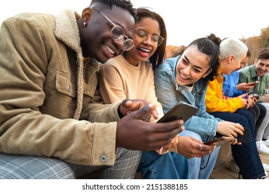 Happy multiracial teen college students having fun using mobile phone together in campus outdoors. - Powered by Shutterstock