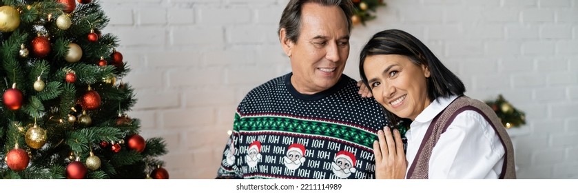 Happy Multiracial Woman Leaning On Smiling Husband Near Decorated Christmas Tree, Banner