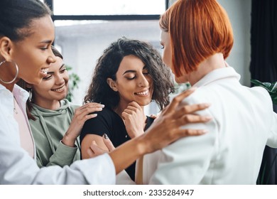 happy multiracial woman smiling with closed eyes near positive multicultural girlfriends and redhead motivation coach in consulting room, self-improvement and mental health concept - Powered by Shutterstock