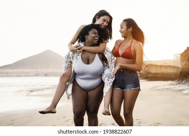 Happy multiracial women with different bodies and skins having fun in summer day on the beach - Main focus on african girl face