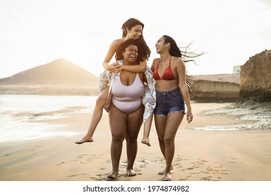 Happy multiracial women with different bodies and skins having fun in summer day on the beach - Soft focus on african girl face - Powered by Shutterstock