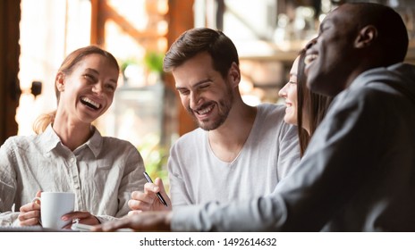 Happy multiracial young friends relax together talking laughing sit at cafe table, cheerful diverse students girls and guys people group studying having fun indoor, multicultural friendship concept - Powered by Shutterstock