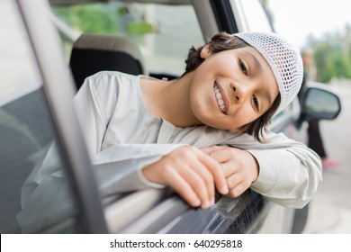 happy muslim boy looking outside car window