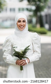happy muslim bride with diamond ring on finger holding wedding bouquet