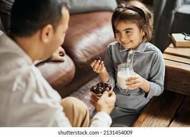 Happy Muslim Daughter Having A Glass Of Milk While Eating Dates With Her Father At Home. 