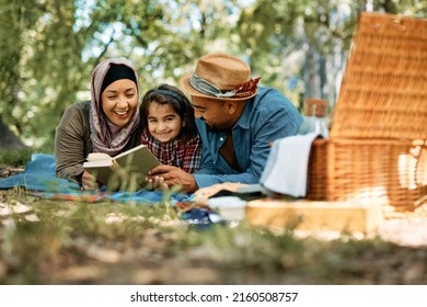 Happy Muslim Family Enjoying In Storytelling While Reading Book During Picnic Day In The Park. Copy Space.