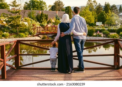 A happy Muslim family enjoying their time together in the park. Romantic Arab couple in love with kid on the summer vacation holiday. Islamic people on the halal travel and tourism. 