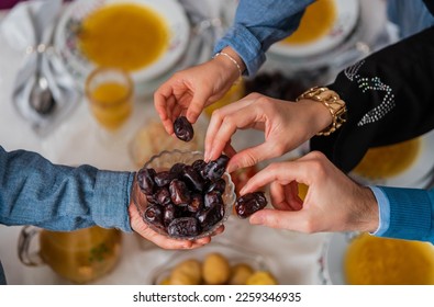 Happy Muslim family having iftar dinner to break fasting during Ramadan dining table at home group of Islamic people eating a healthy food dates together sharing and giving.