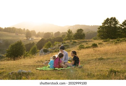 Happy Muslim Family, Mother And Three Children Have Time Together In Nature Sitting And Eating On Green Grass: Touristic Picnic In Travnik, The Mountain Vlasic, Bosnia And Herzegovina