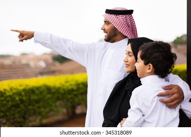 Happy Muslim Family Outside Their Home Pointing