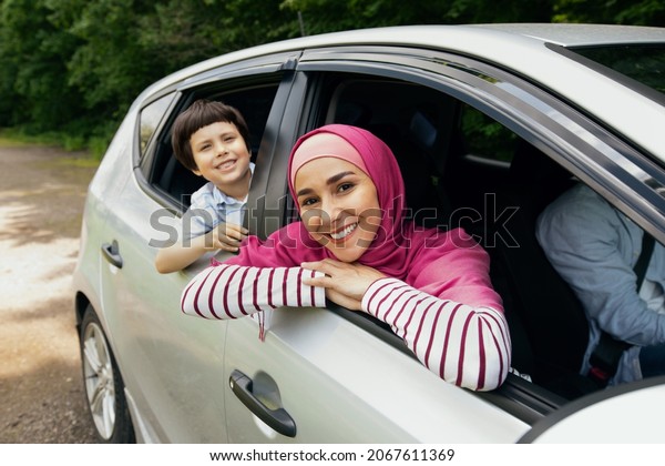 Happy\
Muslim Family Riding Car Together, Smiling Mother In Hijab And Son\
Leaning Out Of Windows, Cheerful Arab Parents And Little Male Child\
Enjoying Travel In Their New Vehicle, Closeup\
Shot