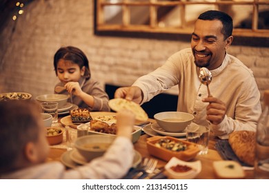 Happy Muslim Father And Son Sharing Pita Bread During Family Meal At Dining Table During Ramadan. 