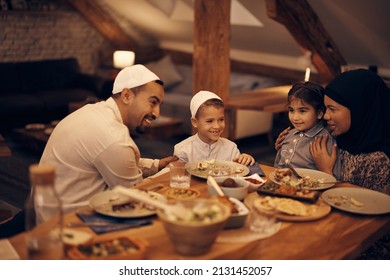 Happy Muslim Kids And Their Parents Communicating During A Meal At Dining Table At Home. 