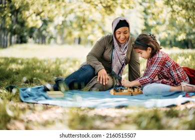 Happy Muslim Mother Playing Chess With Her Daughter In The Park. Copy Space.