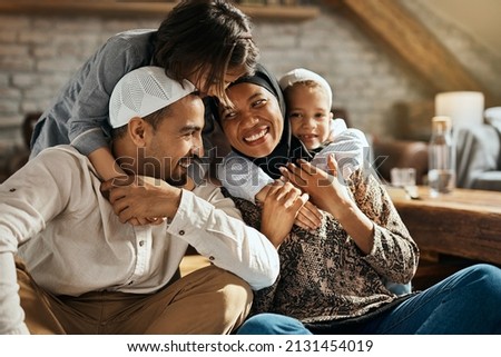 Happy Muslim parents having fun with their children who are embracing them at home. 