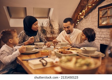 Happy Muslim Parents And Their Kids Having Fun While Eating Dinner At Dining Table During Ramadan. 